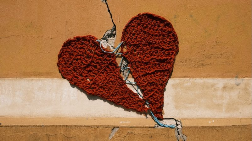 trauma: broken red heart sewn together with yarn