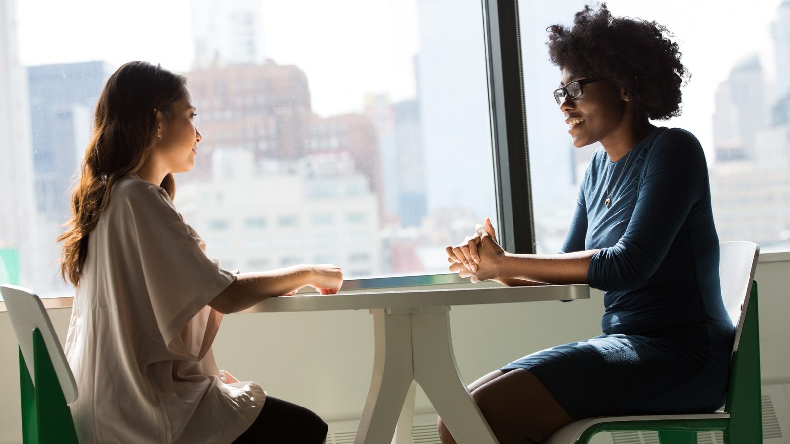 two women sitting at table talking