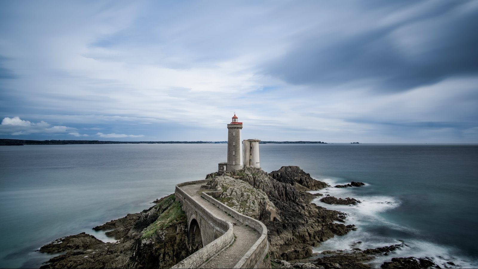 lighthouse on grey coastline with winding path
