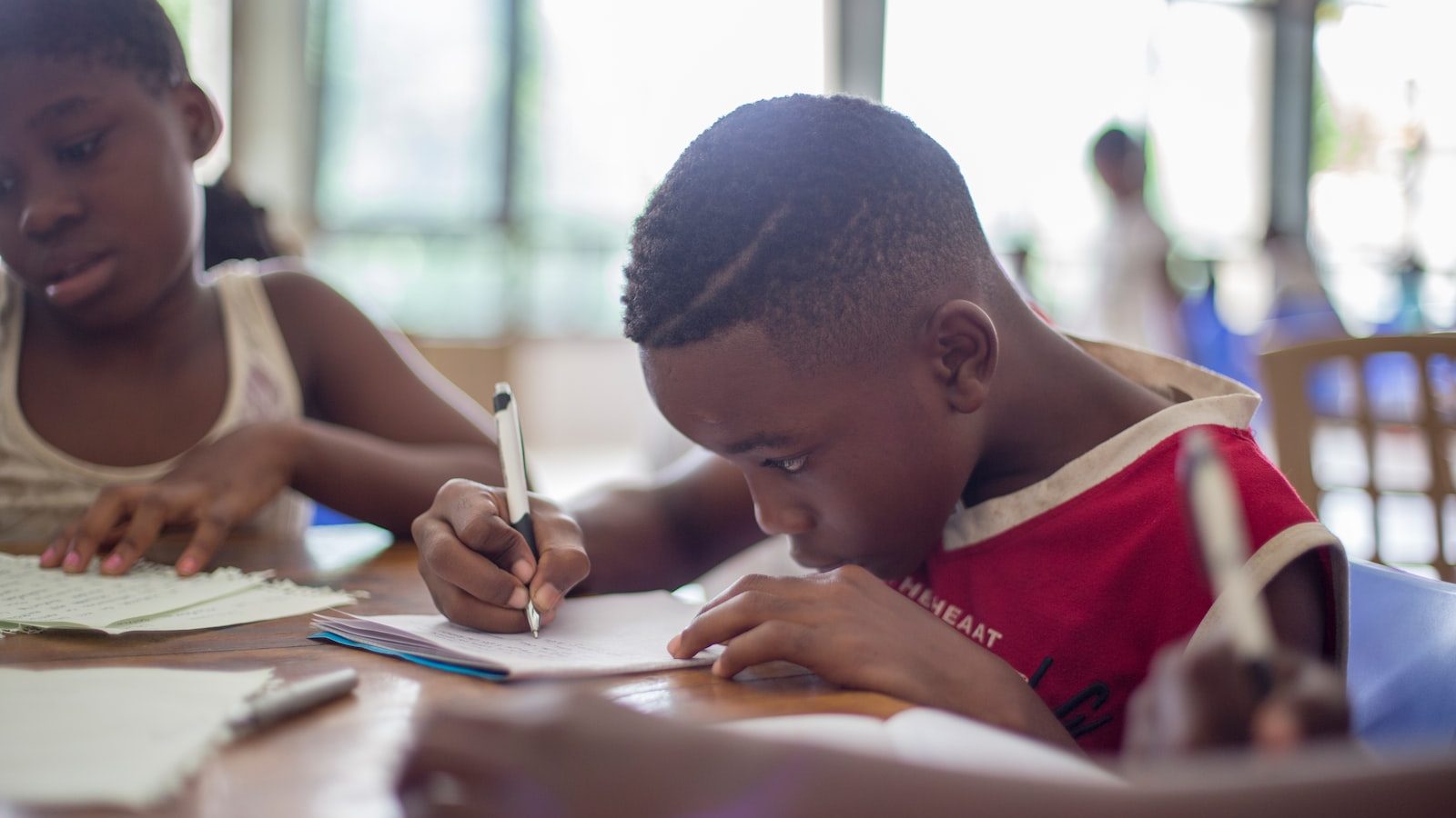 boy writing on printer paper near girl