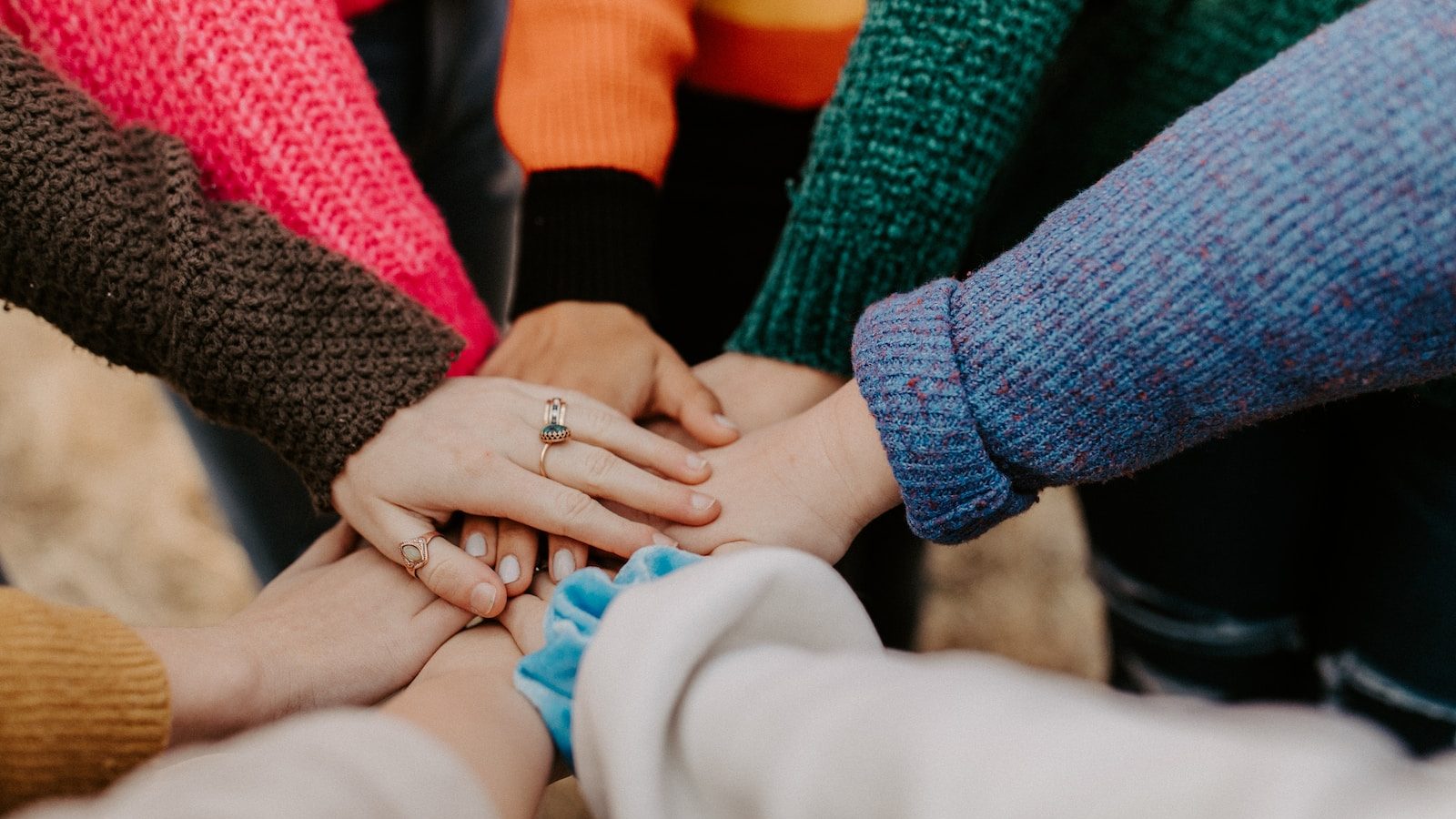 person in red sweater holding babys hand