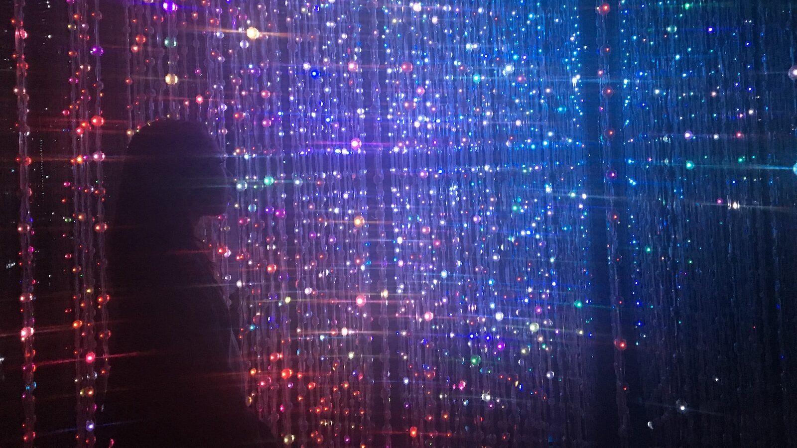 person standing in front of beaded lighted curtains
