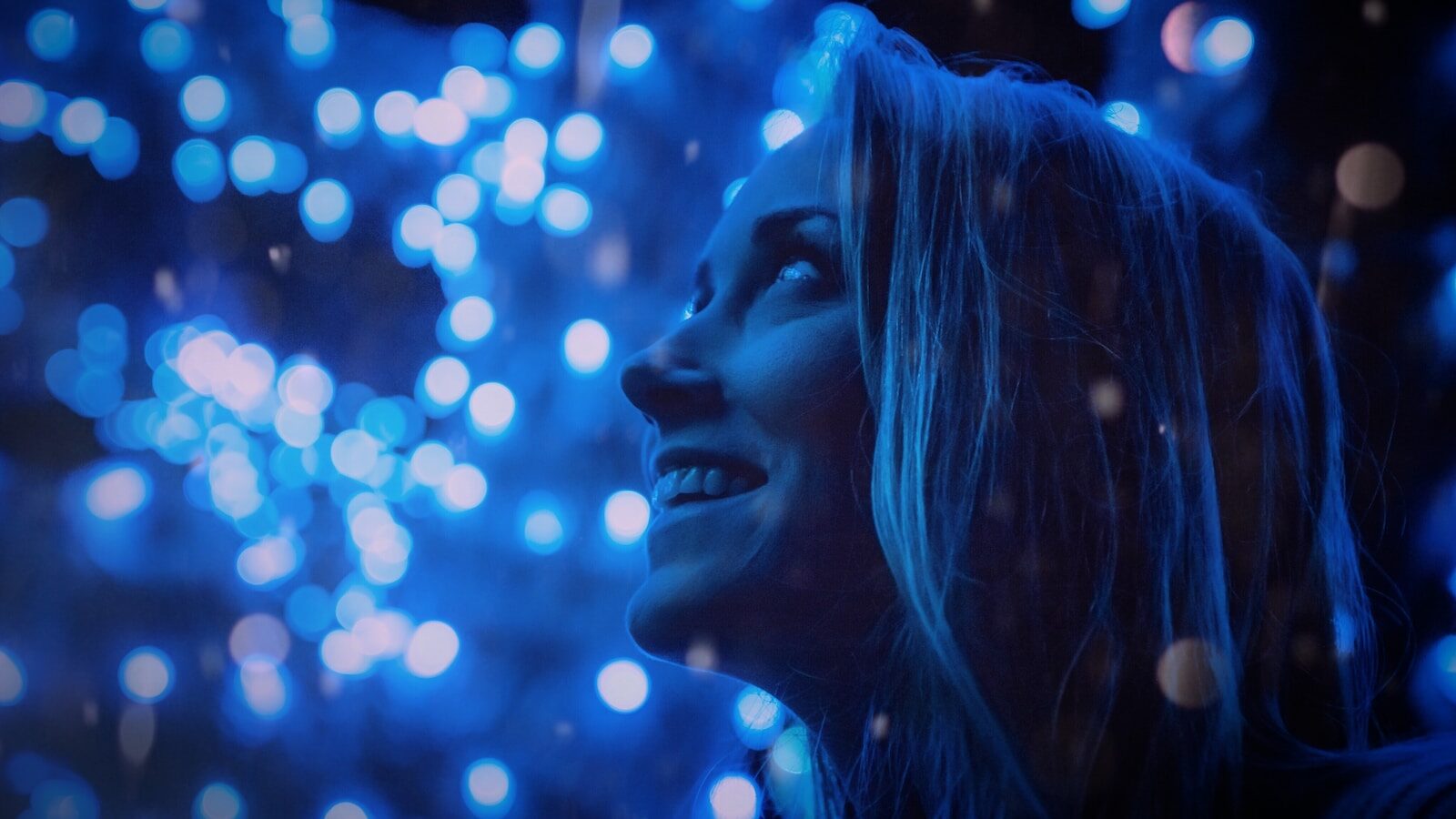 Decorative: AI is helping coach tech providers create personalized development pathways that adapt to client needs. Image description: woman looking at blue lights