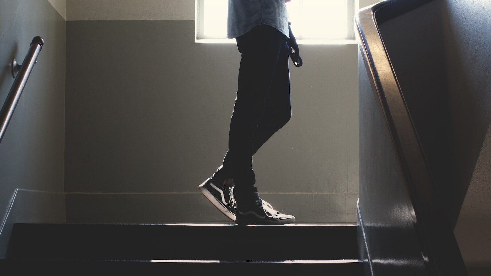 Decorative: EPOG Academy brings AI-empowered coaching to high school students. Image description: person standing on in a dim-lit stair