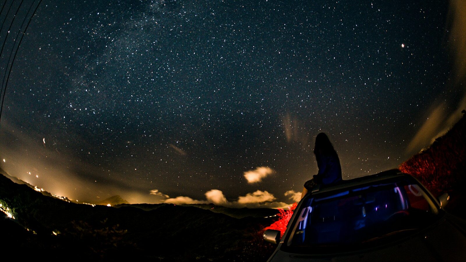 woman sitting on car while watching stars